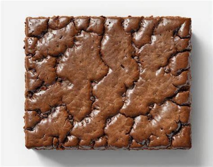 Square brownie on top of another brownie on a piece of parchment paper.