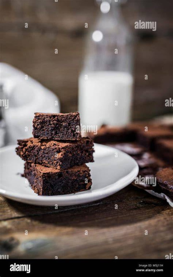 Stack of three homemade brownies on parchment paper.